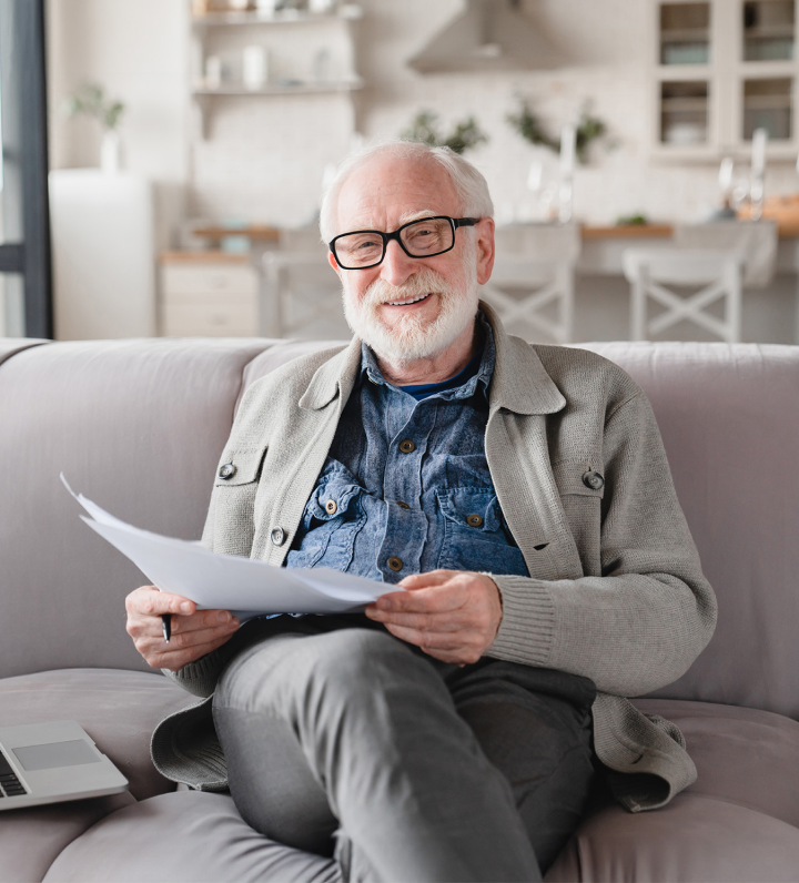 man smiling on couch with document