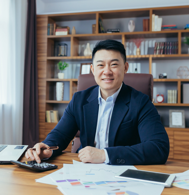 man at desk smiling with calculator