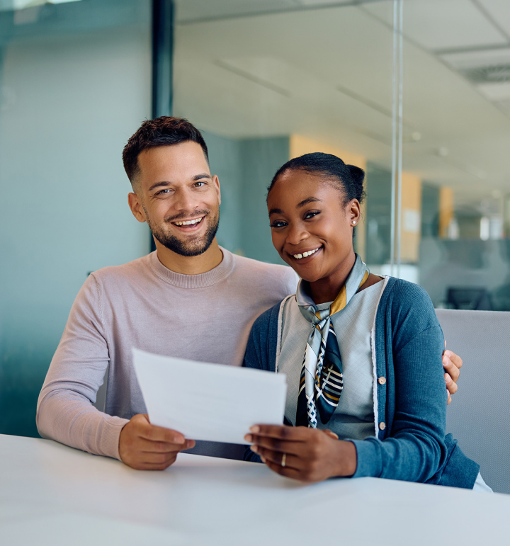 two people smiling and holding a document