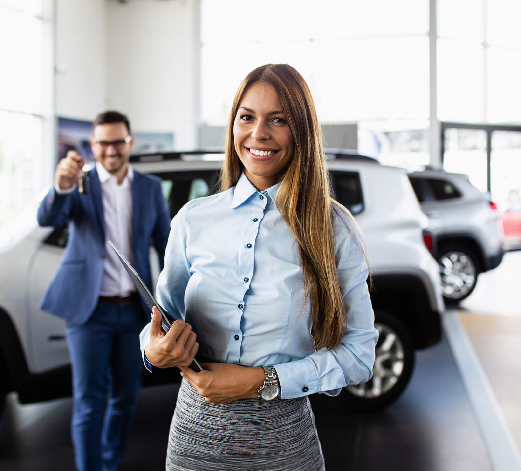 woman at car dealership holding clipboard