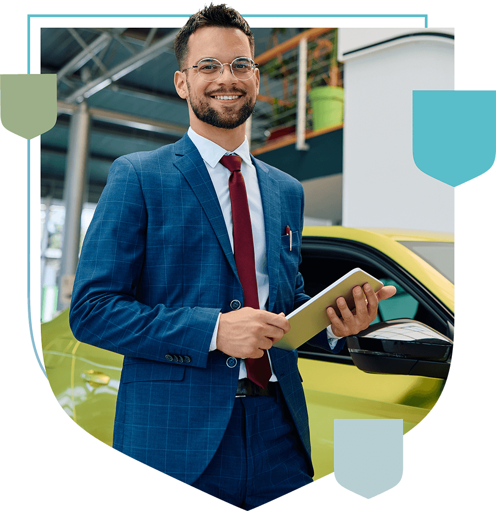 man at car dealership smiling and holding a notebook